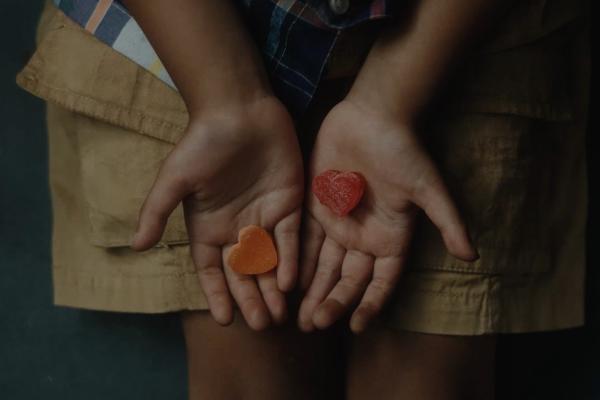 Overhead photo of child's two hands holding heart-shaped candies