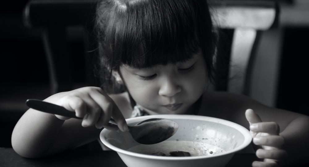 Young girl eating out of bowl with spoon