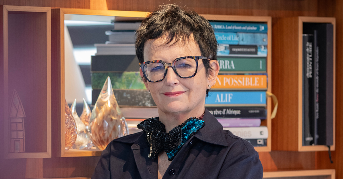 Patou Nuytemans standing in front of a bookshelf