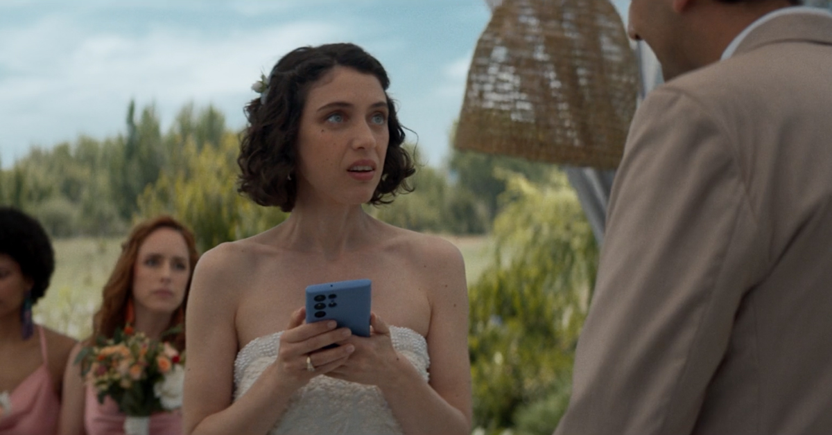 Bride holding a phone looking skeptically at groom during daytime wedding ceremony