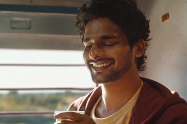 Man holding a cup of tea while riding a train