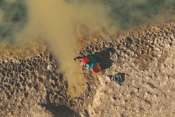 Overhead shot of a person in a sandy desert retreiving water 