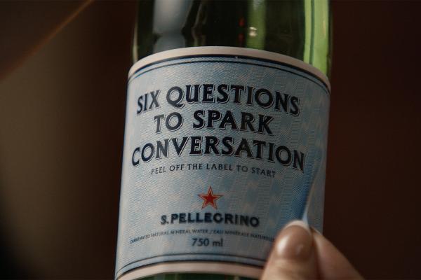 San Pellegrino bottle with a label that says "Six Questions to Spark Conversation" in all caps writing