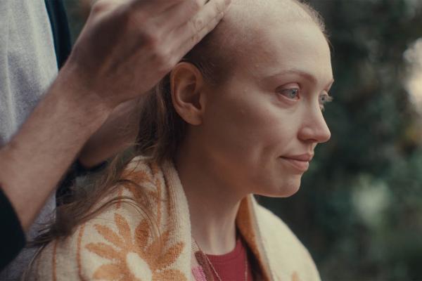 Person sitting outside having their hair cut 