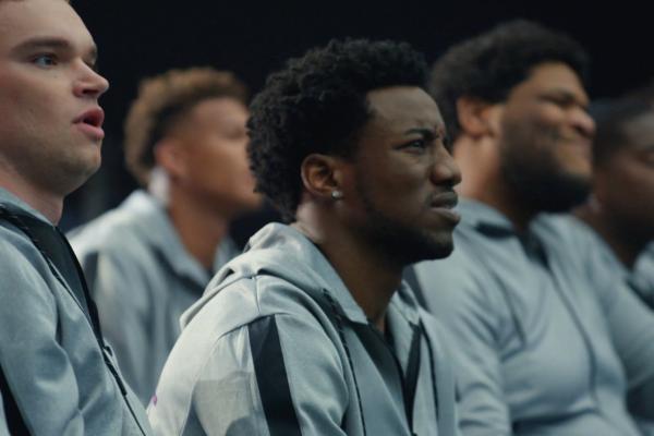 Four young football prospects sit and watch a lecture attentively 