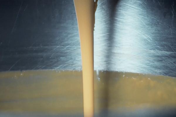 Cheese whey being poured into a large steel container