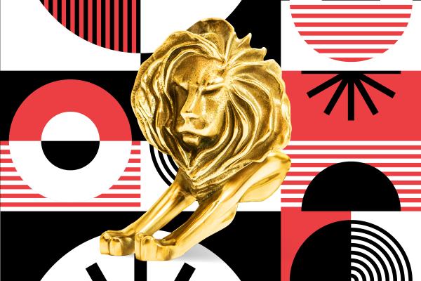 Gold Cannes Lions trophy in front of a red, white, and black patterned background