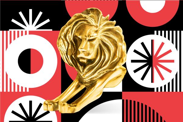 Gold Cannes Lions trophy in front of a red, white, and black patterned background
