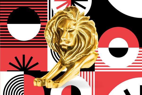 Gold Cannes Lions trophy in front of a red, white, and black patterned background