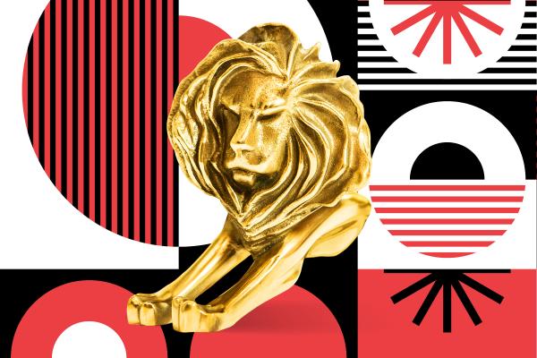 Gold Cannes Lions trophy in front of a red, white, and black patterned background