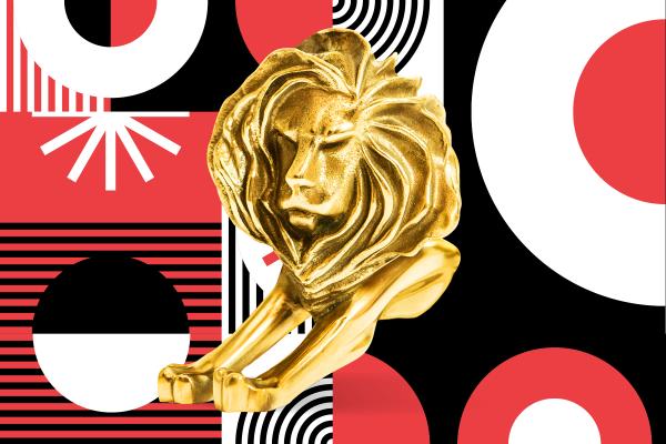 Gold Cannes Lions trophy in front of a red, white, and black patterned background
