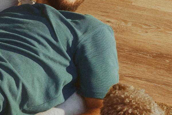 A man lying on his back on a mat while looking at his dog