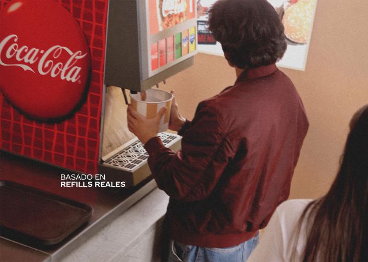 Real Refills — Coca-Cola image of someone filling up a large bucket with Coca-Cola from a soda fountain. White copy overlaid: "Basado en refills reales"