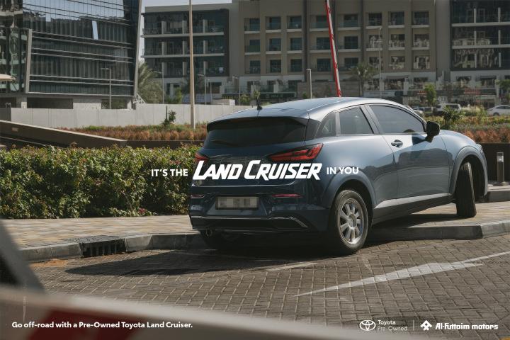 It's the Land Cruiser in you — Al-Futtaim Toyota blue car with front wheels parked on curb and back wheels parked on road. White copy overlay "It's the Land Cruiser in You"