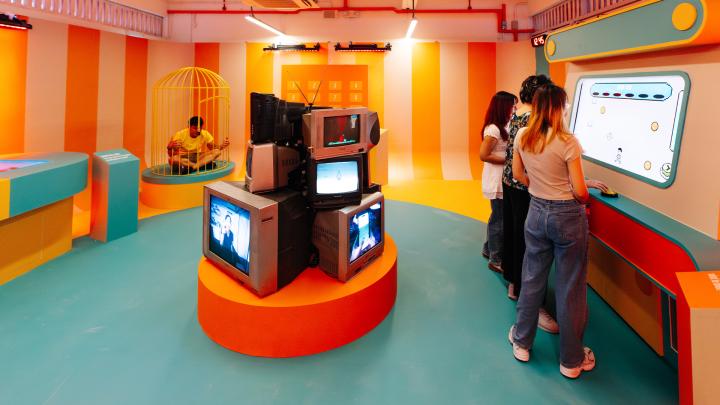 Uninfluenced — Singapore Central Nacrotics Bureau Three people interacting with a screen in a colorful escape room game