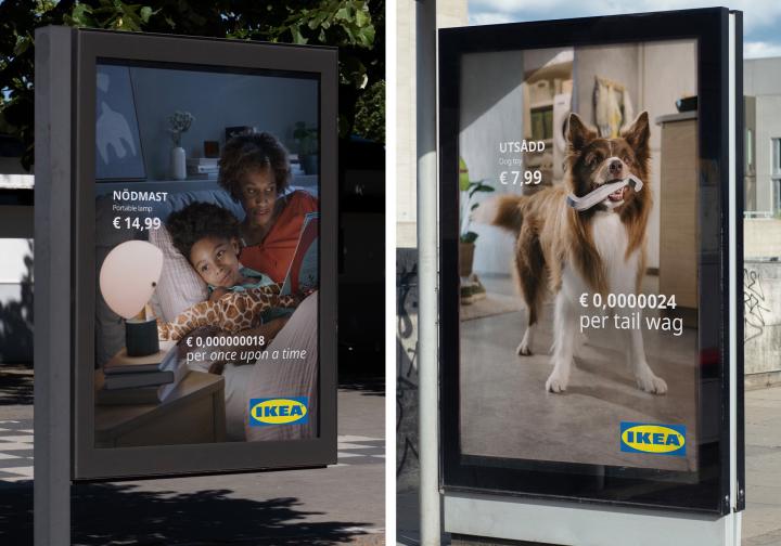 Two IKEA billboard stands side by side outdoors. The left poster advertises the NÖDMAST portable lamp (€14.99) showing a mother reading to her child with the text "€ 0,000000018 per once upon a time." The right poster advertises the UTSÄDD dog toy (€7.99), showing a brown and white dog holding a toy in its mouth with the text "€ 0,0000024 per tail wag."