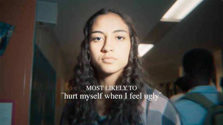 Most Likely To—Dove Girl in school hallway looking into camera. White overlay text: "most likely to hurt myself when i feel ugly"