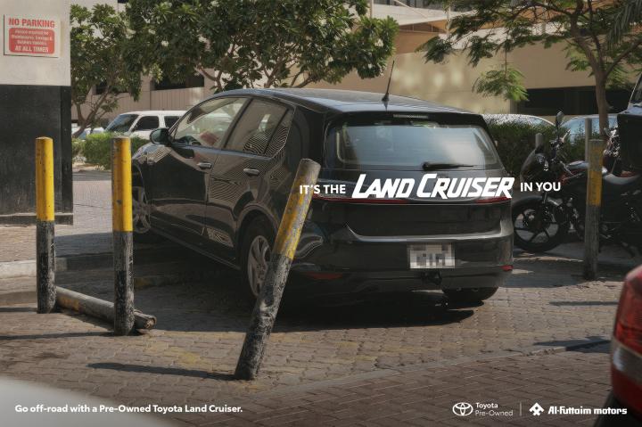 It's the Land Cruiser in you — Al-Futtaim Toyota Car parked in odd location, between black and yellow bollards. White copy overlay, "It's the Land Cruiser in You"