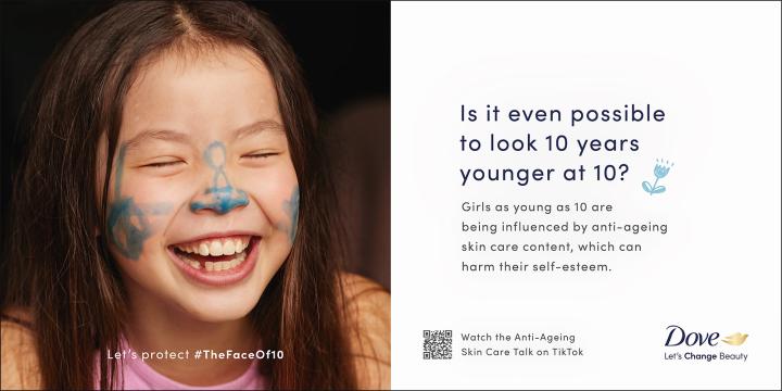 #TheFaceof10 — Dove Young brown haired girl smiling with blue paint doodles on her nose and cheeks. The text of the image says: "Is it even possible to look 10 years younger at 10? Girls as young as 10 are being influenced by anti-ageing skin care content, which can harm their self-esteem." And a QR code and the copy "Watch the Anti-Ageing Skin Care Talk on TikTok". There is a Dove logo in the bottom right with the tagline "Let's Change Beauty"