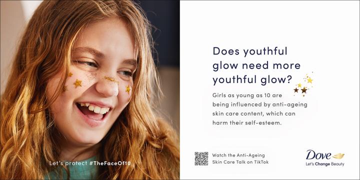 #TheFaceof10 — Dove Young red haired girl smiling with gold glittered painted stars on her face. The text of the image says: "Does youthful glow need more youthful glow? Girls as young as 10 are being influenced by anti-ageing skin care content, which can harm their self-esteem." And a QR code and the copy "Watch the Anti-Ageing Skin Care Talk on TikTok". There is a Dove logo in the bottom right with the tagline "Let's Change Beauty"