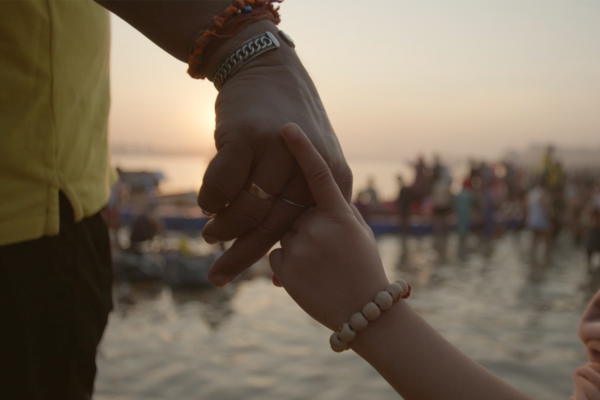Child with guardian beads holding an adults hand