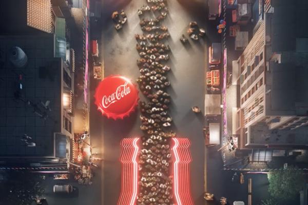 overhead shot of crowd in a queue in the shape of a coca cola bottle. to the left of the queue is a large red coca cola bottle cap