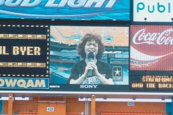 Woman singing on jumbotron that has Coca-Cola branding