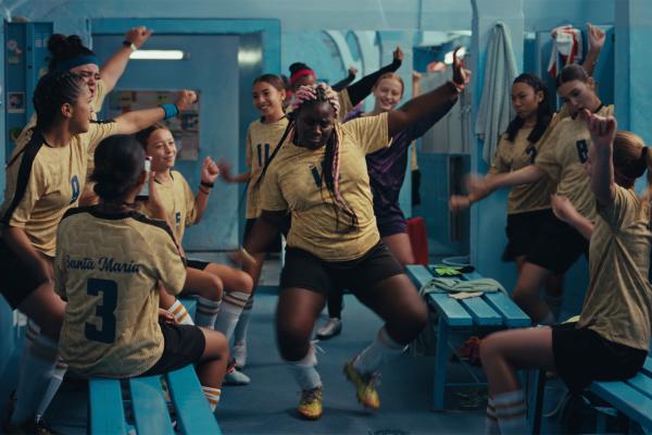 Tem of young girls soccer players dancing with joy in a locker room