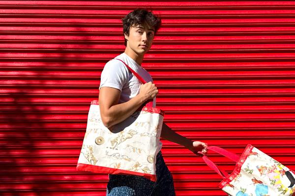 Person walking outside in front of red background carrying two Jimmy Dean Griddle Bags