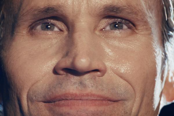Close-up of a man's face, focusing on his eyes and mouth with a neutral expression.