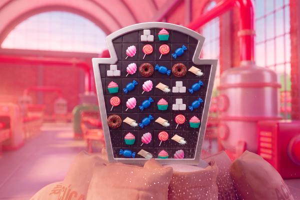 3D rendering of a match-three style puzzle board shaped like the iconic Heinz keystone label, filled with candy-themed game icons including lollipops, cupcakes, cotton candy, and sugar packets, set against a warm, pink-hued factory background.