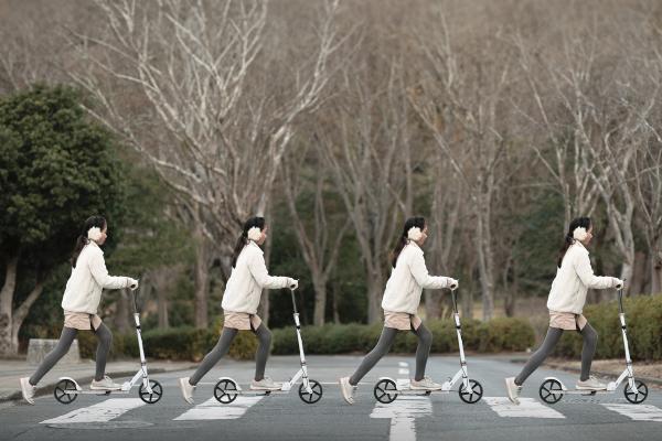 Four time Repeating image of a woman on a scooter crossing a street in a crosswalk