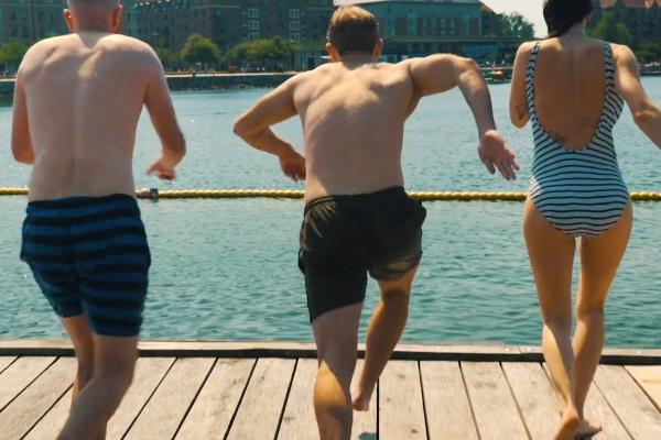Three people in swimsuits standing on a dock overlooking water