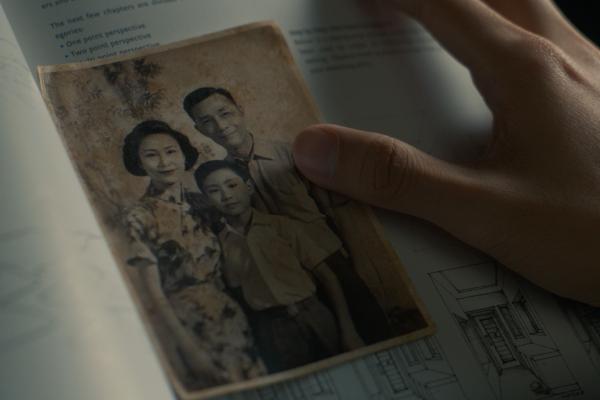 Hand touching an old photograph of a father, mother and child