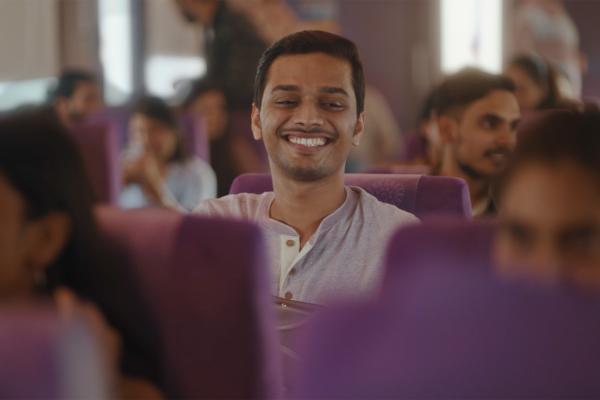 Man smiling on a train with purple seats