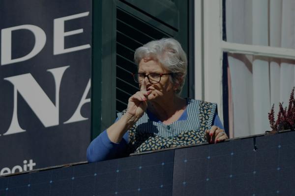 Italian woman standing on a balcony looking down at the street below