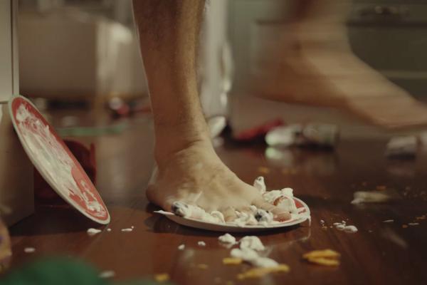 Bare foot stepping on a messy paper plate indoors
