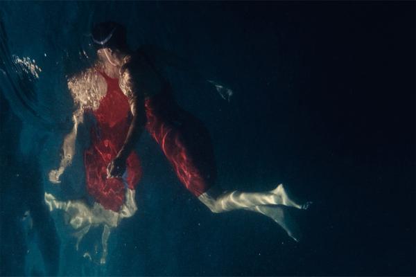 Shot of competitive swimmer in red suit with reflection in the water