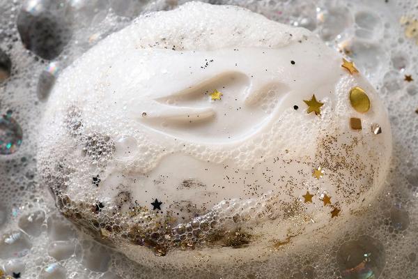 Dove soap bar with suds and pieces of gold confetti on it