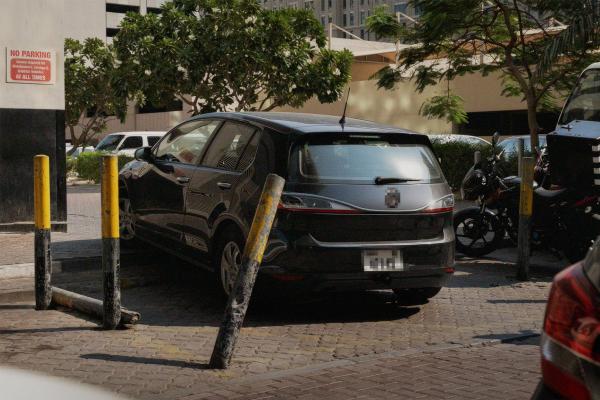 Car parked in odd location, between black and yellow bollards