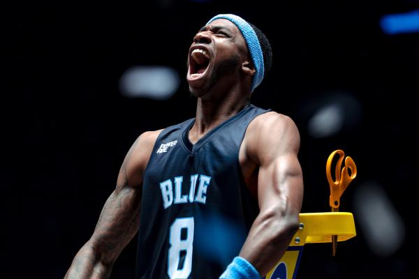 Basketball player in navy blue jersey and headband yelling in celebration 
