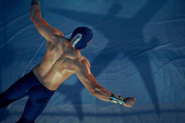 Wrestler with arms spread open jumping into a wrestling ring