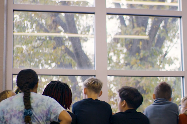 Children at school looking out a large wall of windows