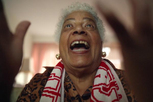 Football fan wearing scarf watching game with excited expression