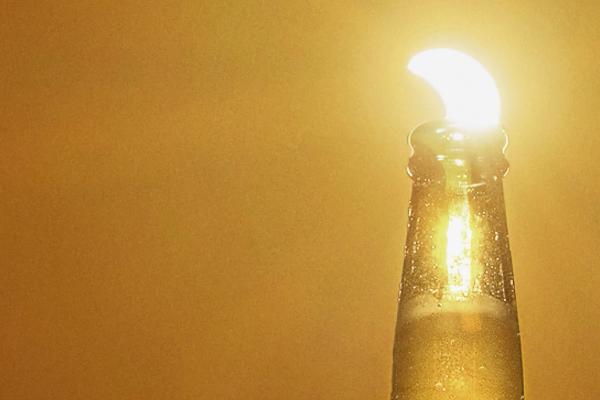 Eclipse sun appearing as a lime wedge in a Corona bottle