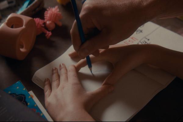 Picture of child's hands making a circle while an adult hand draws inside the children's hands