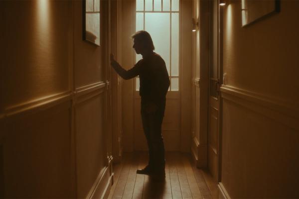 Silhoutted person in a hallway reaching for a door