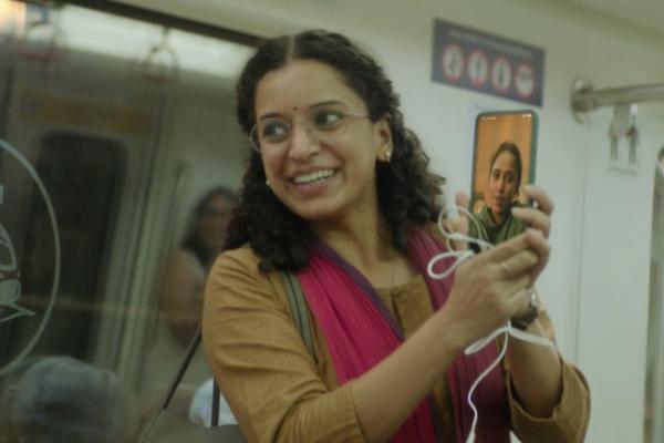 Woman holding phone smiling while on a subway train