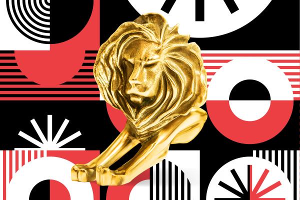 Gold Cannes Lions trophy in front of a red, white, and black patterned background
